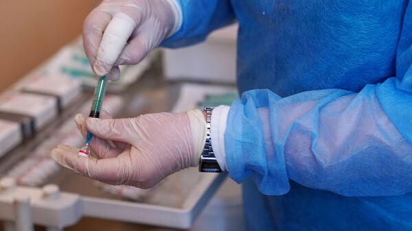 Медицинский работник держит в руке вакцину от COVID-19 - Sputnik Узбекистан