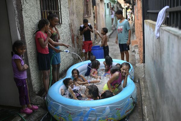 Дети играют в надувном бассейне на одной из улиц Каракаса, Венесуэла. - Sputnik Узбекистан