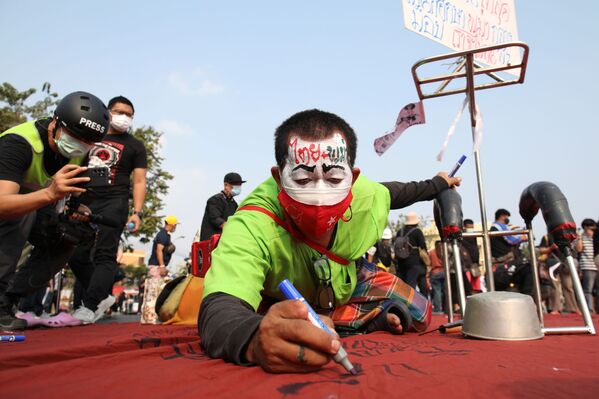 Протестующий пишет на ткани во время акции протеста в Бангкоке. - Sputnik Узбекистан