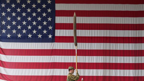 Amerikanskiy soldat derjit flag vo vremya voyennoy tseremonii v kazarmax Shtork v Illesxayme, Germaniya - Sputnik Oʻzbekiston