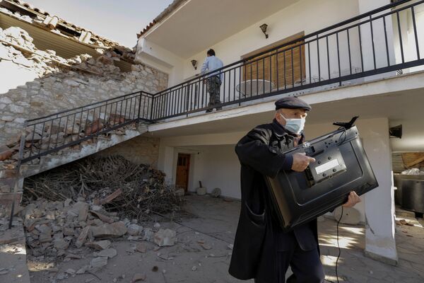 Мужчина с телевизором у поврежденного дома, деревня Дамаси, Греция, 3 марта 2021 г. - Sputnik Узбекистан