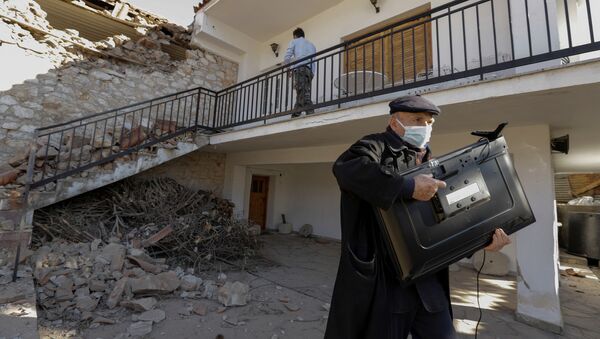 Мужчина с телевизором у поврежденного дома вследствие землетрясения в Греции  - Sputnik Узбекистан