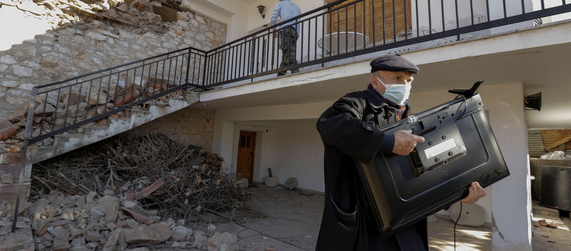 Мужчина с телевизором у поврежденного дома вследствие землетрясения в Греции  - Sputnik Узбекистан, 1920, 04.03.2021