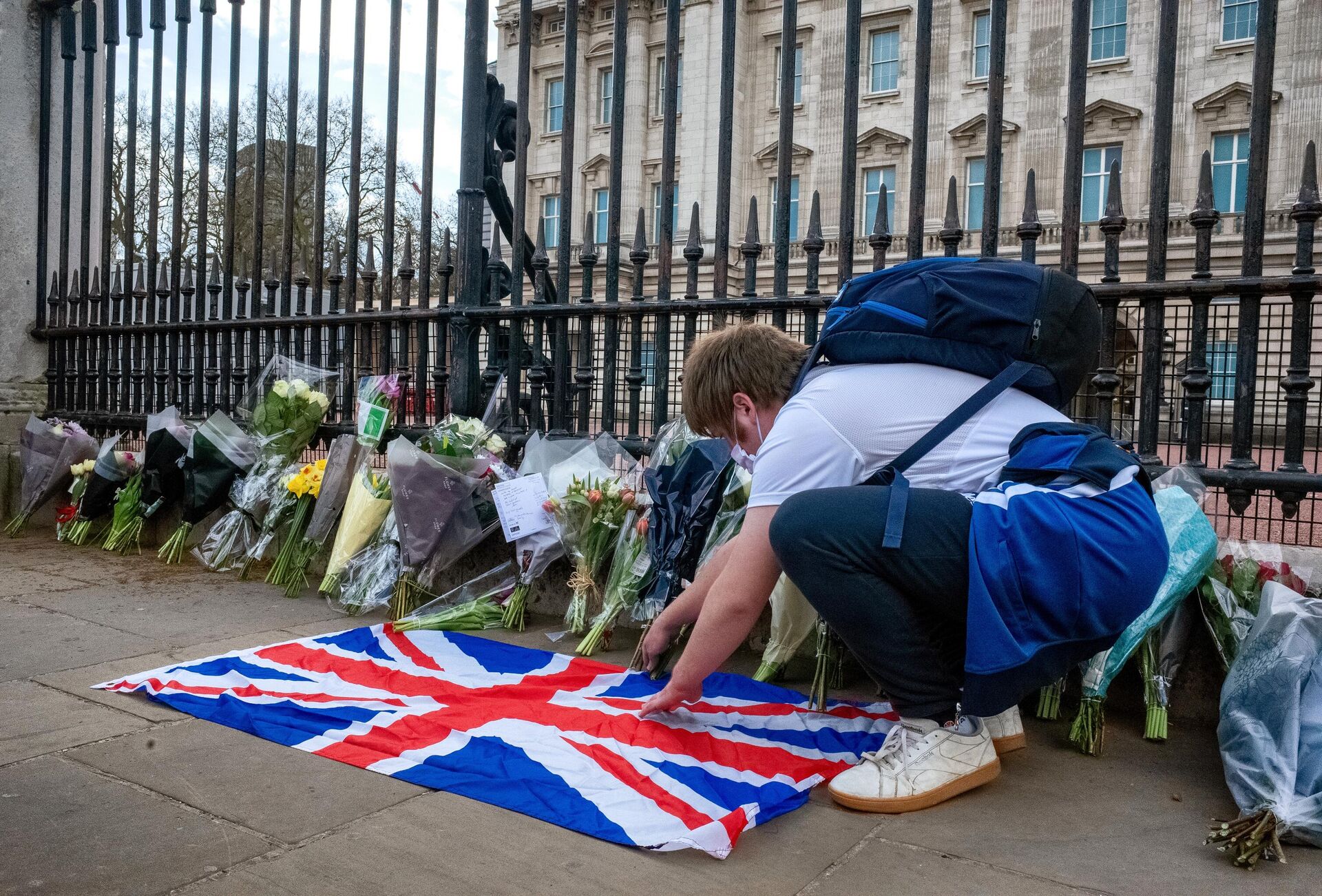 Люди несут цветы к Букингемскому дворцу в Лондоне в память о супруге королевы Великобритании Елизаветы II принце Филиппе, герцоге Эдинбургском - Sputnik Узбекистан, 1920, 11.04.2021