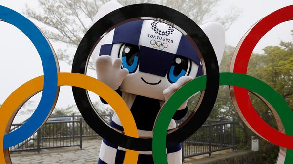 Талисман Летней Олимпиады в Токио Miraitowa позирует сзади Олимпийских колец после мероприятия по случаю 100 дней до Олийписких игр в Токио  - Sputnik Ўзбекистон