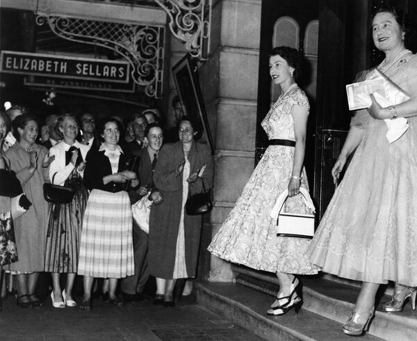Елизавета II и ее мать, королева Елизавета, приветствуют прохожих, когда выходят из нового театра в Лондоне 4 августа 1955 года. Королева-мать отметила свое 55-летие.  - Sputnik Узбекистан