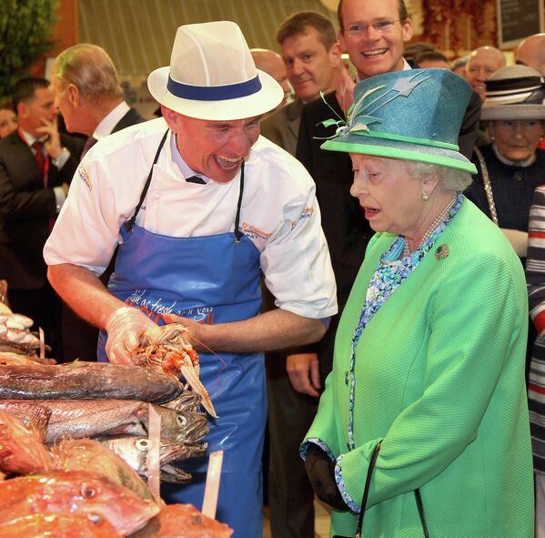 Королева Великобритании Елизавета II разговаривает с торговцем рыбой во время посещения английского рынка в Корке в последний день своего четырехдневного визита в Ирландию, 20 мая 2011 года. - Sputnik Узбекистан