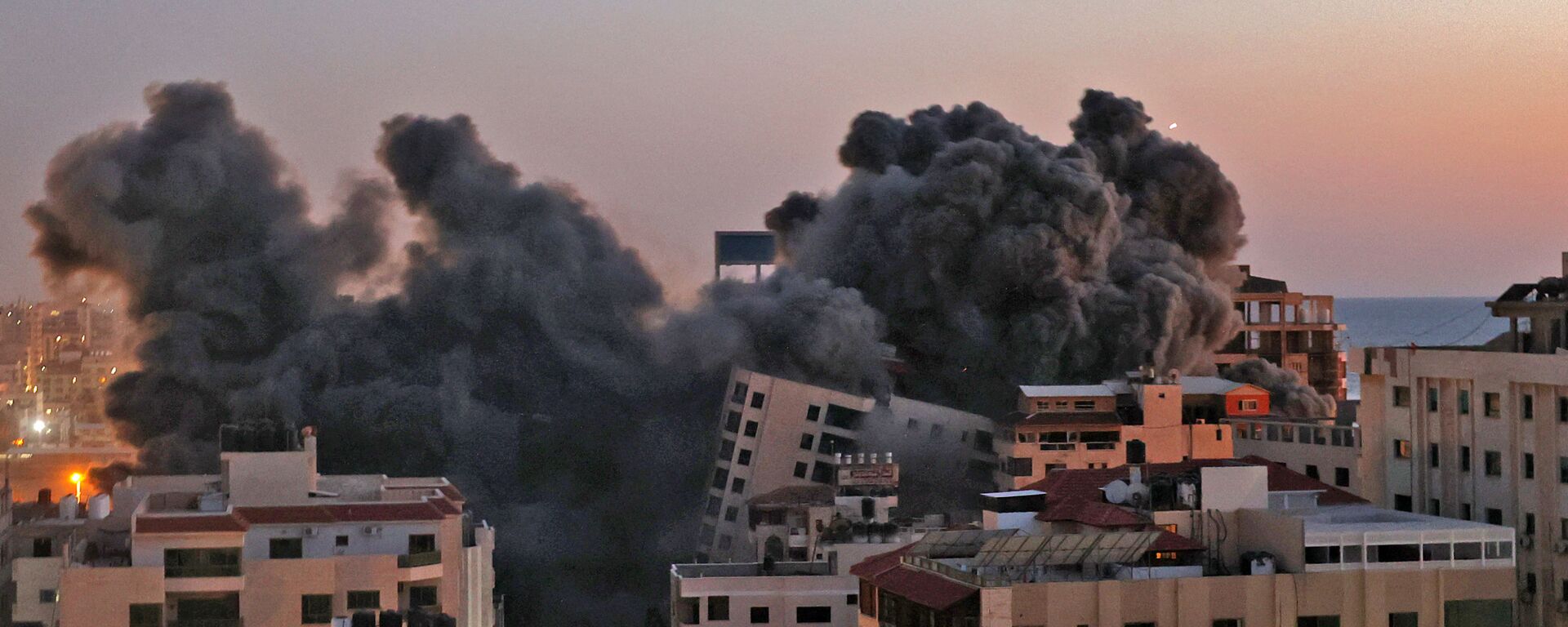Пожарные тушат горящие многоквартирные дома после израильских авиаударов в городе Газа - Sputnik Ўзбекистон, 1920, 15.05.2021