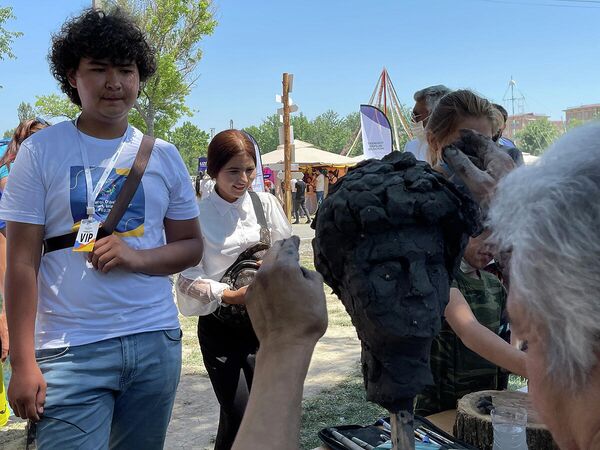 Участник фестиваля позирует для скульптора, показывающего свой мастер-класс. - Sputnik Узбекистан