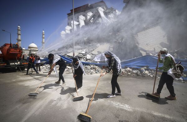 Палестинские добровольцы и муниципальные служащие расчищают завалы комплекса Ханади, недавно разрушенного израильскими ударами, в районе Римал города Газа. - Sputnik Узбекистан