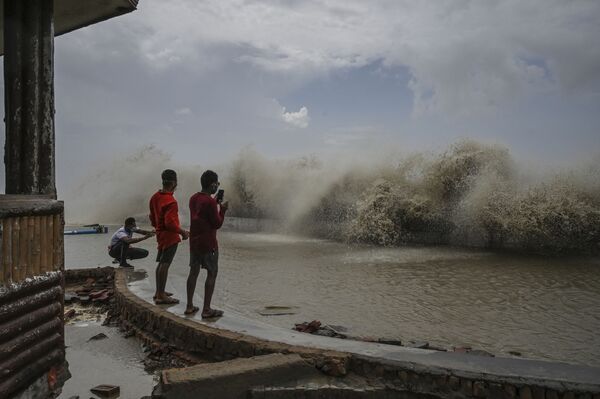 Жители фотографируют волны, набегающие на береговую линию после того, как циклон Яас обрушился на восточное побережье Индии в Бенгальском заливе в Дигхе. - Sputnik Узбекистан