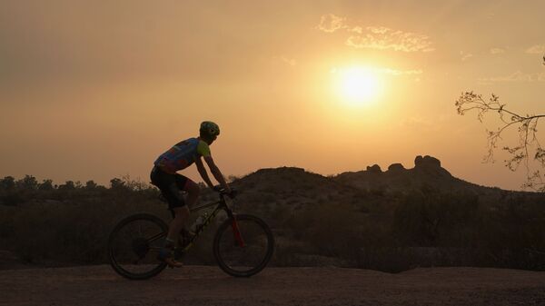 Велосипедист во время заката в жаркий день в США  - Sputnik Узбекистан
