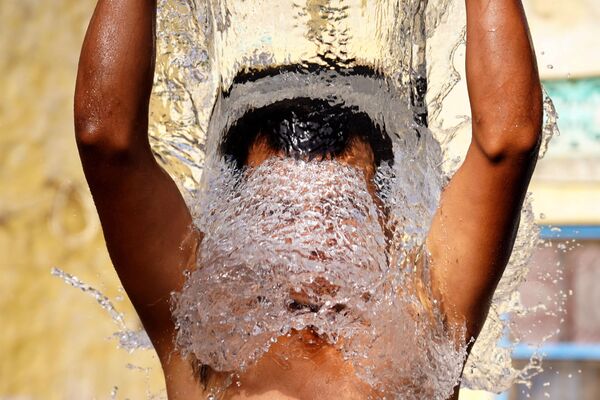 Мужчина обливается водой в индийском Аджмере. - Sputnik Узбекистан