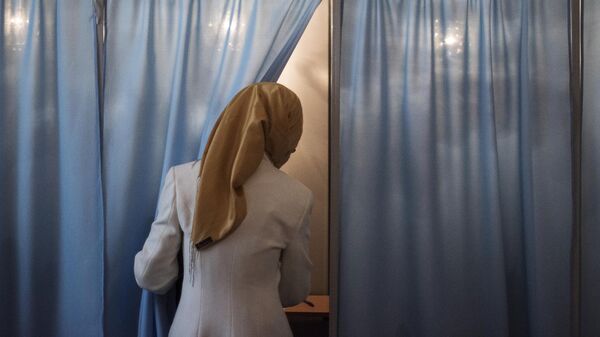Женщина голосует на избирательном участке во время выборов президента Узбекистана. Архивное фото - Sputnik Узбекистан