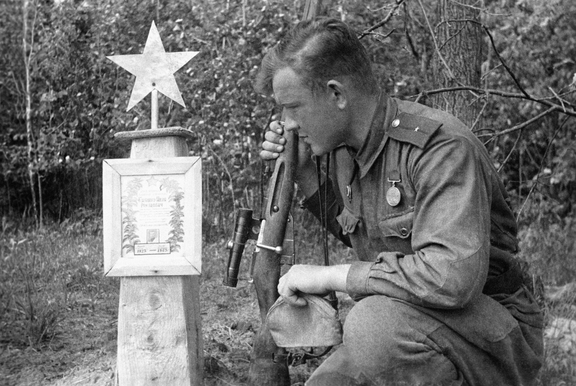 Снайпер 61-й армии, младший лейтенант Александр Лебедев (на его счету 307 убитых фашистов) у могилы своего боевого товарища. Брянский фронт - Sputnik Узбекистан, 1920, 21.06.2021