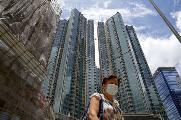 Женщина в маске для предотвращения распространения коронавируса гуляет перед жилым комплексом Grand Central в Гонконге. - Sputnik Узбекистан