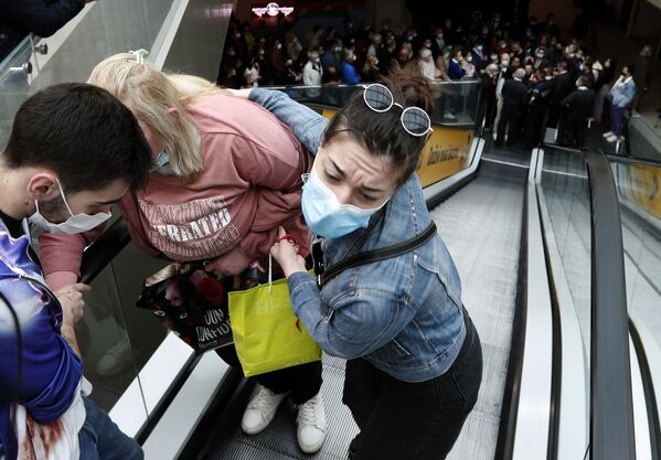 Женщине помогают подняться по эскалатору, пока люди выстраиваются в очередь, чтобы пройти вакцинацию и стать одним из 100 человек, получивших купоны на покупку в торговом центре Usce в Белграде, Сербия. - Sputnik Узбекистан