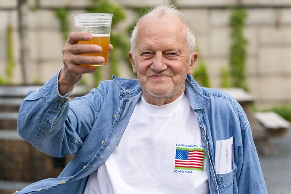 Джордж Рипли в возрасте 72-х лет держит свое бесплатное пиво после прививки от COVID-19  в Центре Кеннеди в Вашингтоне.  - Sputnik Узбекистан