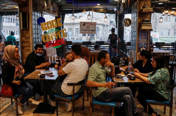 В Багдаде посетители сидят в кафе, которое предлагает бесплатный кофе для людей, получивших вакцину от коронавируса. - Sputnik Узбекистан