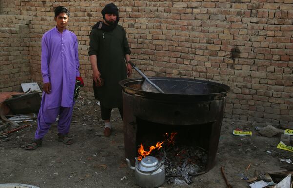 Люди готовят еду во временном лагере для пострадавших в результате боевых действий на одной из улиц Кабула.  - Sputnik Узбекистан