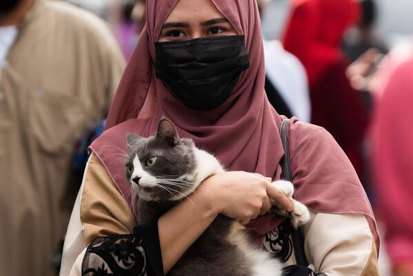 В Филиппинах мусульманка в медицинской маске несет кошку после утренней молитвы в Курбан-хайит возле Голубой мечети в городе Тагиг, метро Манила, Филиппины. - Sputnik Узбекистан