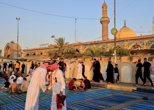 Иракские верующие обмениваются приветствиями после молитвы, совершенной в честь празднования Курбан-хайита, на улице возле мечети Абу Ханифа в районе Багдад Адхамия, Ирак. - Sputnik Узбекистан
