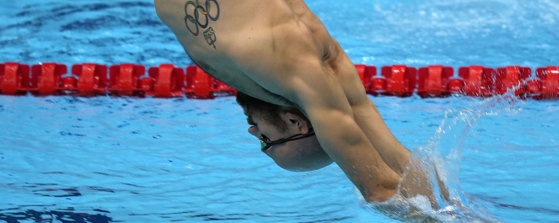 Пловец с олимпийской татуировкой делает упражнения во время тренировки на летних Олимпийских играх 2020  - Sputnik Узбекистан, 1920, 28.07.2021