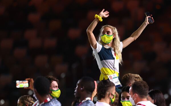 Австралийка сидит на плечах участника своей команды во время церемонии закрытия токийской Олимпиады.  - Sputnik Узбекистан