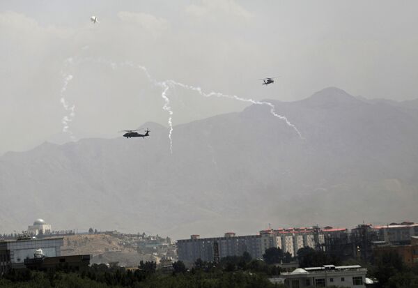 Американский военный вертолет Black Hawk и дирижабль в небе над столицей Афганистана. Заняв пригороды Кабула, талибы пообещали не захватывать город силой при условии мирной передачи власти. Власти в спешке покинули город, на территорию американского посольства прилетели военные вертолеты. - Sputnik Узбекистан