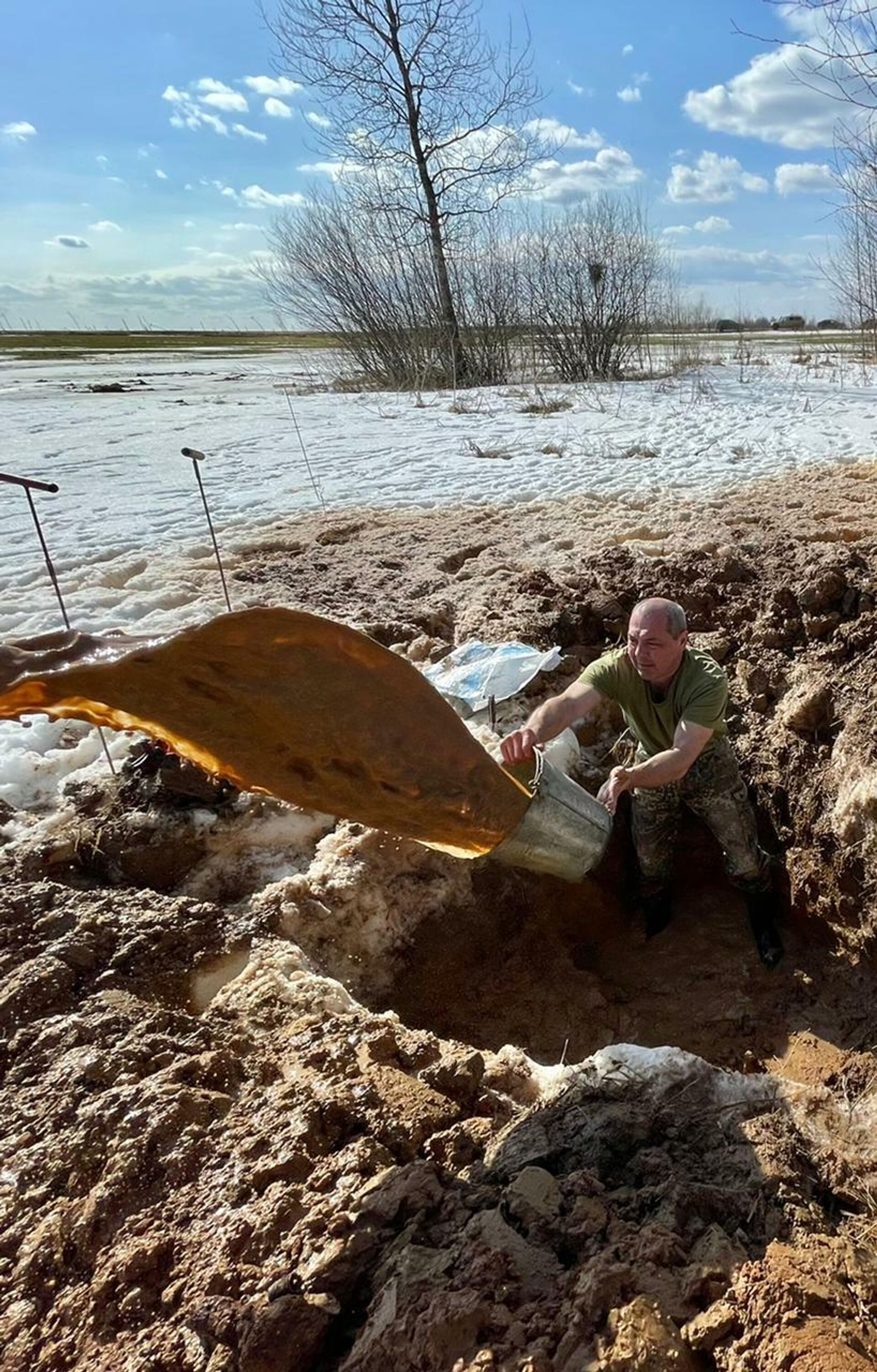 Участник отряда Сергей Бобылев откачивает талую воду из весеннего раскопа - Sputnik Узбекистан, 1920, 16.08.2021