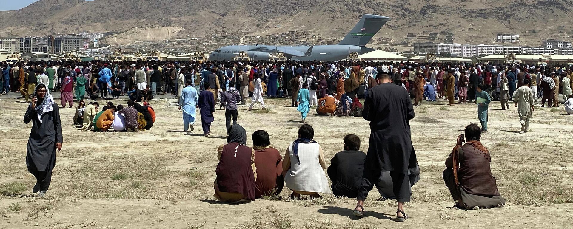 Сотни людей собрались возле транспортного самолета C-17 ВВС США на периметре международного аэропорта в Кабуле - Sputnik Узбекистан, 1920, 31.08.2021