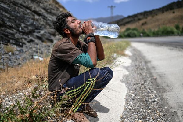Афганский беженец пьет воду, сидя на обочине дороги в турецкой провинции Битлис, 15 августа 2021 г. - Sputnik Узбекистан