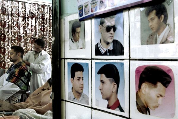 В парикмахерской на стене висят фотографии, на которых изображены разные стили стрижки без бороды, Кабул, 2002 год. - Sputnik Узбекистан