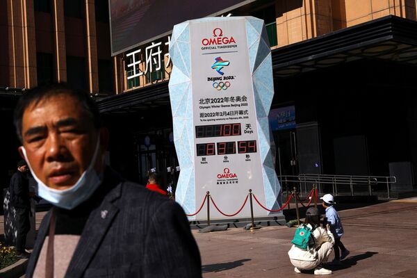 Прохожий на фоне табло с обратным отсчетом, показывающим время, оставшееся до Олимпиады в Пекине-2022. - Sputnik Узбекистан