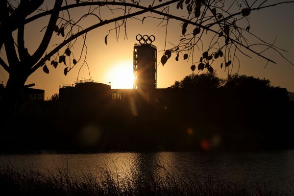 Здание, увенчанное олимпийскими кольцами, в парке Шоуган неподалеку от олимпийских построек в Пекине на фоне заката. - Sputnik Узбекистан