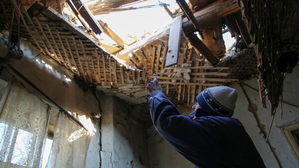 42-летний житель Донецка демонстрирует состояние своего дома на улице Дружбы, в крышу которого попал снаряд - Sputnik Узбекистан