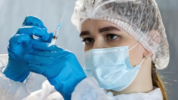 Медицинский сотрудник подготавливает шприц для вакцинации посетителей  - Sputnik Ўзбекистон