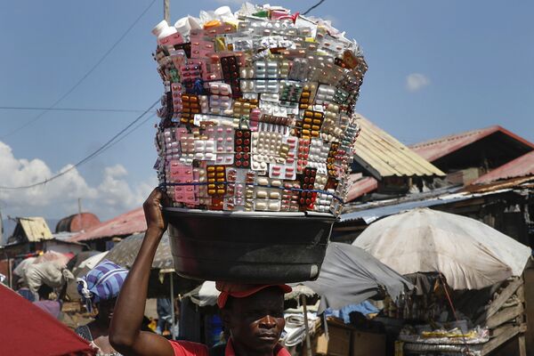 Уличный торговец несет лекарства на рынке Croix des Bosalles в Порт-о-Пренсе (Гаити), 3 ноября. - Sputnik Узбекистан