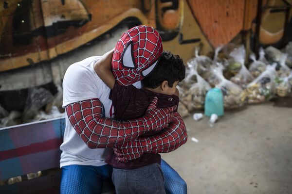 Волонтер в костюме Человека-паука обнимает ребенка в Рио-де-Жанейро (Бразилия), 30 октября. - Sputnik Узбекистан