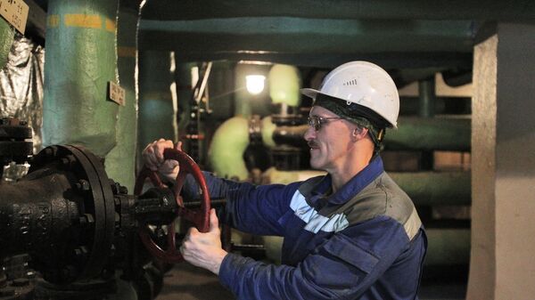 Рабочий поворачивает вентиль на трубах в котельной в подвале жилого многоквартирного дома - Sputnik Ўзбекистон