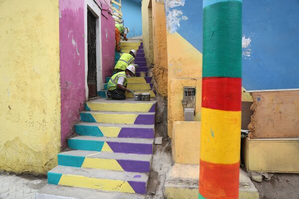 Рабочие раскрашивают лестницу под цвет ярких стен соседних домов. - Sputnik Узбекистан