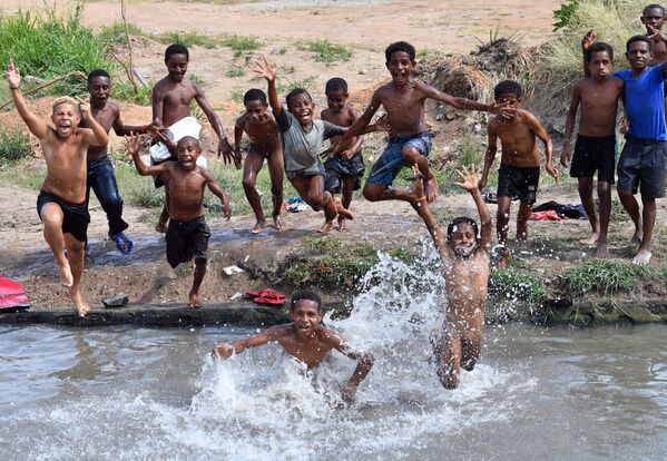 Дети прыгают в небольшой пруд, чтобы избавиться от жары на окраине Порт-Морсби,  19 ноября 2018 г. - Sputnik Узбекистан