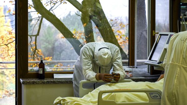 Медицинский работник рядом с пациентом в отделении интенсивной терапии больницы Лозенец в Софии - Sputnik Узбекистан