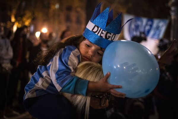 Девочка на плечах у матери во время церемонии прощания с Диего Марадоной в Барселоне, Испания, 26 ноября 2020 года. - Sputnik Узбекистан