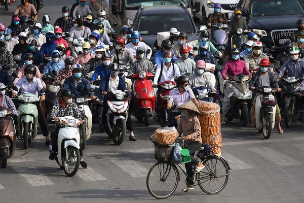 Торговец хлебом проезжает мимо мотоциклистов, ждущих на перекрестке зеленого света, Ханой, 2 июня 2021 года. - Sputnik Узбекистан