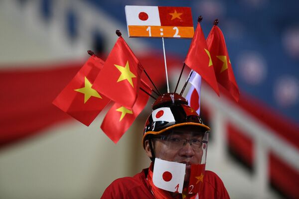 Футбольный болельщик с флагами Вьетнама и Японии на кепке перед квалификационным матчем между сборными двух стран в рамках чемпионата мира по футболу в Катаре. - Sputnik Узбекистан