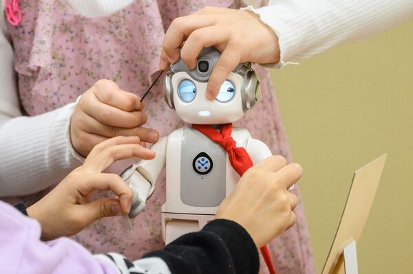 Дети играют с 24-сантиметровым роботом &quot;Альфа Мини&quot;, который умеет петь, танцевать и даже учить кунг-фу. В школе Мару в Сеуле начали использовать роботов-малышей в качестве помощников в детском саду. - Sputnik Узбекистан