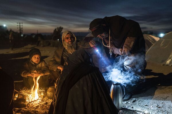 Семья готовит чай в лагере возле офиса Управления по чрезвычайным ситуациям в Герате, Афганистан, 29 ноября 2021 г. Около 2000 человек покинули свои дома в деревне Аллахьяр в провинции Гор из-за засухи. - Sputnik Узбекистан