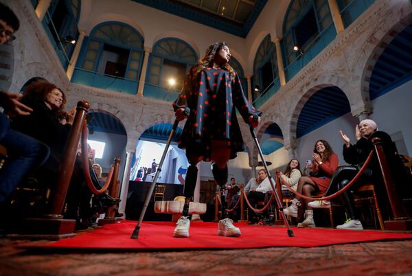 Женщина на протезах ходит на костылях во время модного показа, призванного изменить понимание стандартов красоты, в Тунисе 27 ноября 2021 г. - Sputnik Узбекистан