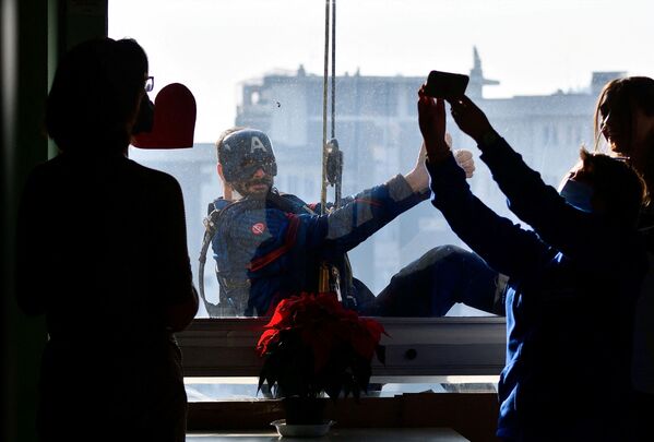 Человек в костюме Капитана Америки заглядывает в окно педиатрического отделения. - Sputnik Узбекистан